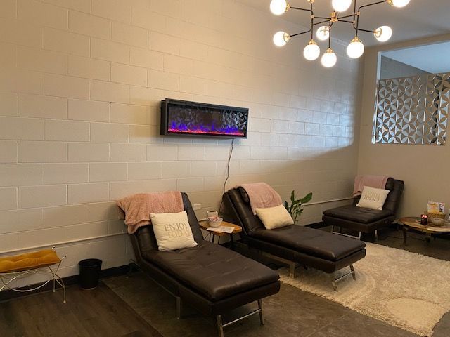 Modern waiting room with lounge chairs, wall art, chandelier, and a neon-lit feature on the wall