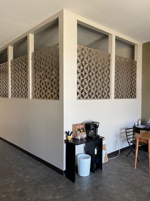 Cafe interior with a white partition wall, decorative lattice panels, and a small coffee station corner