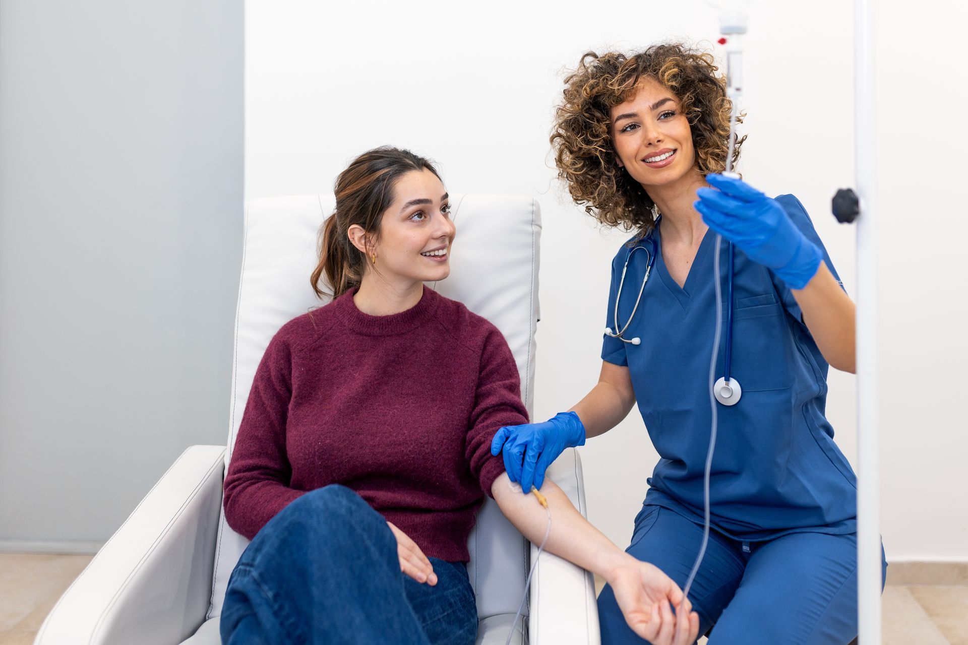 Patient smiling with a clinician in blue scrubs during a checkup in a medical office