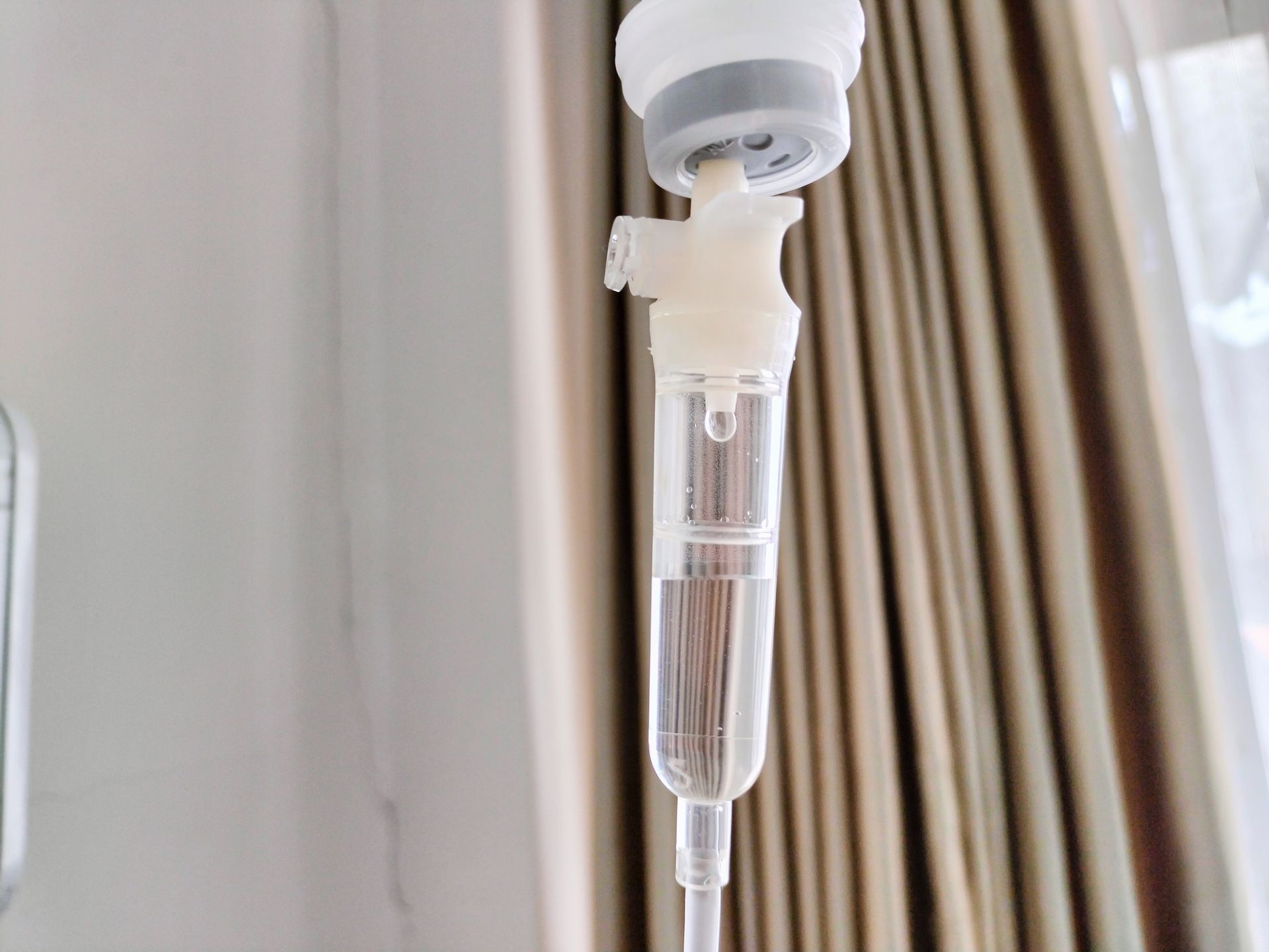 Close-up of a hanging IV drip with clear fluid in a hospital setting