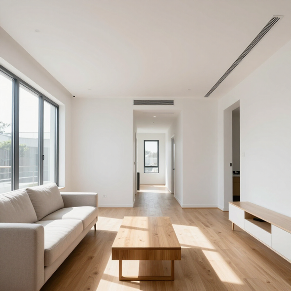 Bright minimalist living room with white sofas, wooden coffee table, and sunlight on hardwood floor