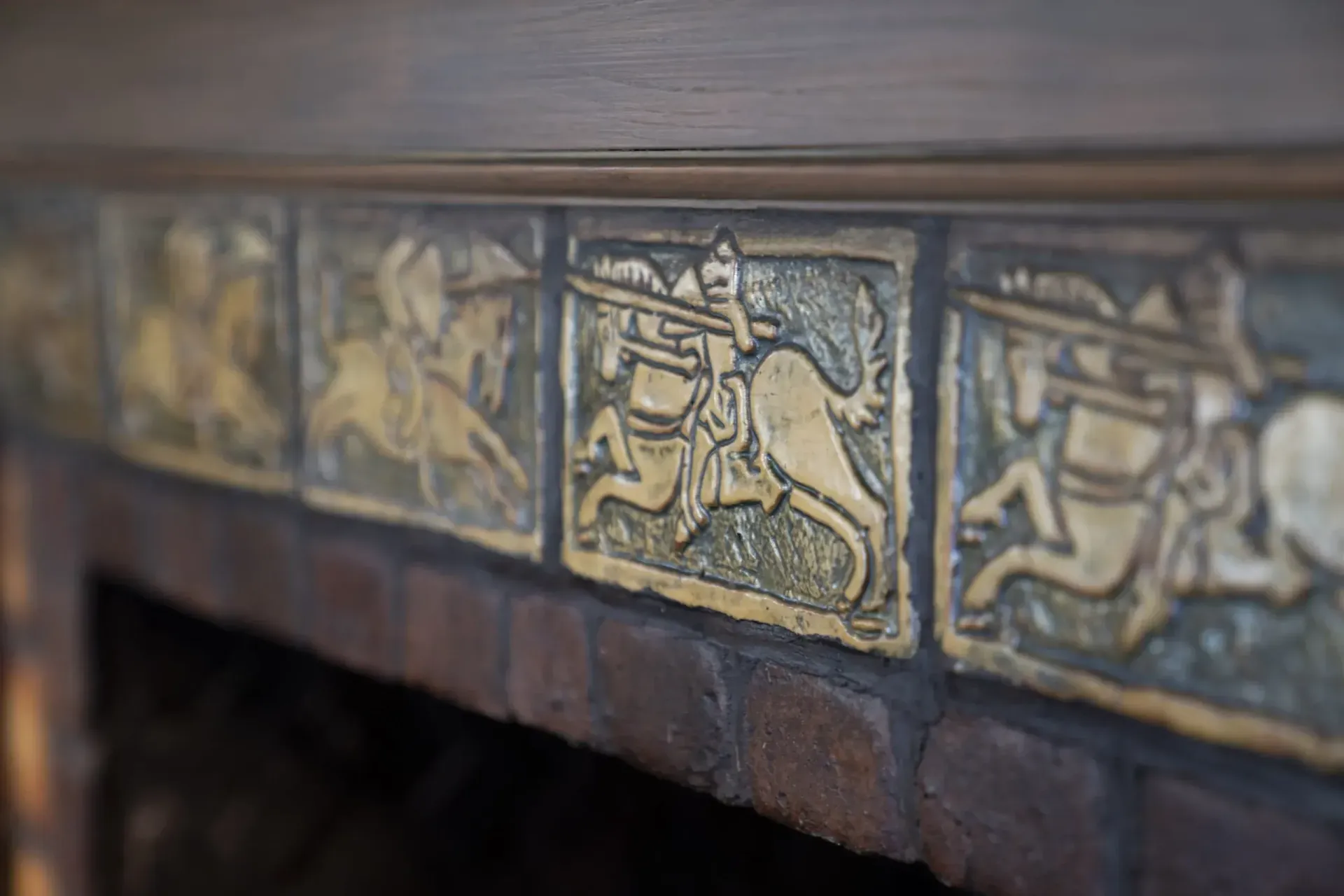Close-up of ornate glazed tiles on a fireplace or mantel with blue and gold patterns