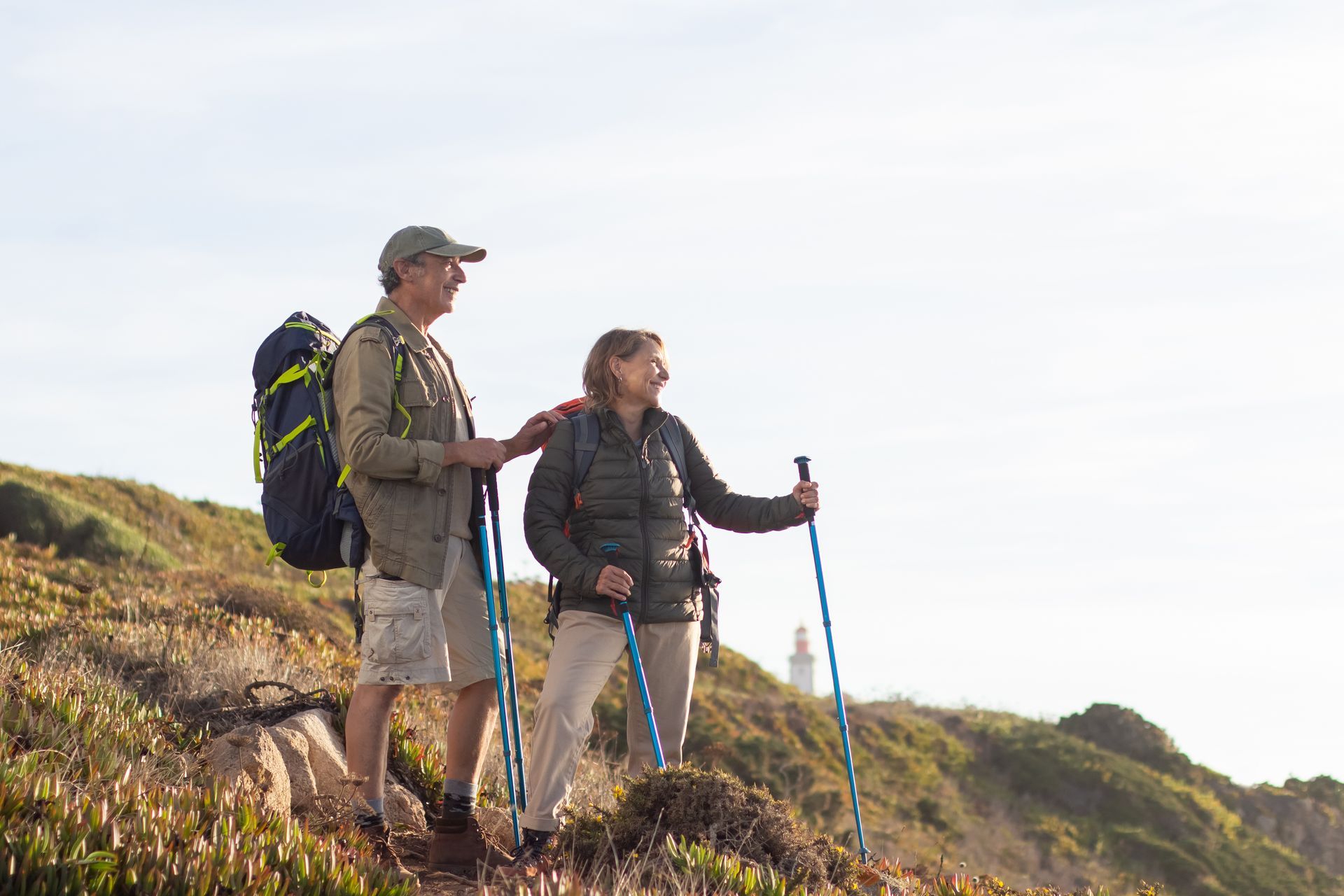 Two hikers using trekking poles walk along a scenic trail, highlighting healthy aging, mobility, and