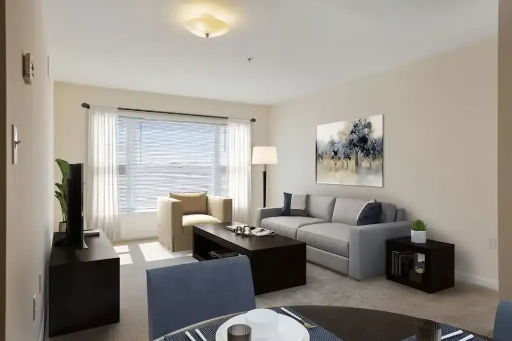 Bright living room with gray sofa, armchair, coffee table, floor lamp, and large window with blinds