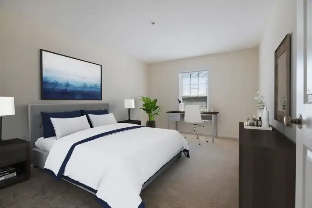 Modern hotel bedroom with a large bed, desk, lamps, and a window view.