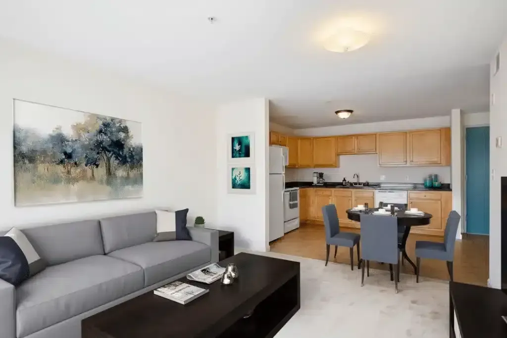 Modern living room with gray sofa, black coffee table, and open kitchen with dining table and chairs