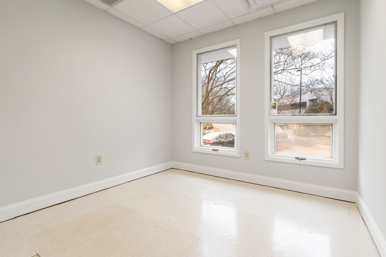 Empty white room with bright windows and light flooring