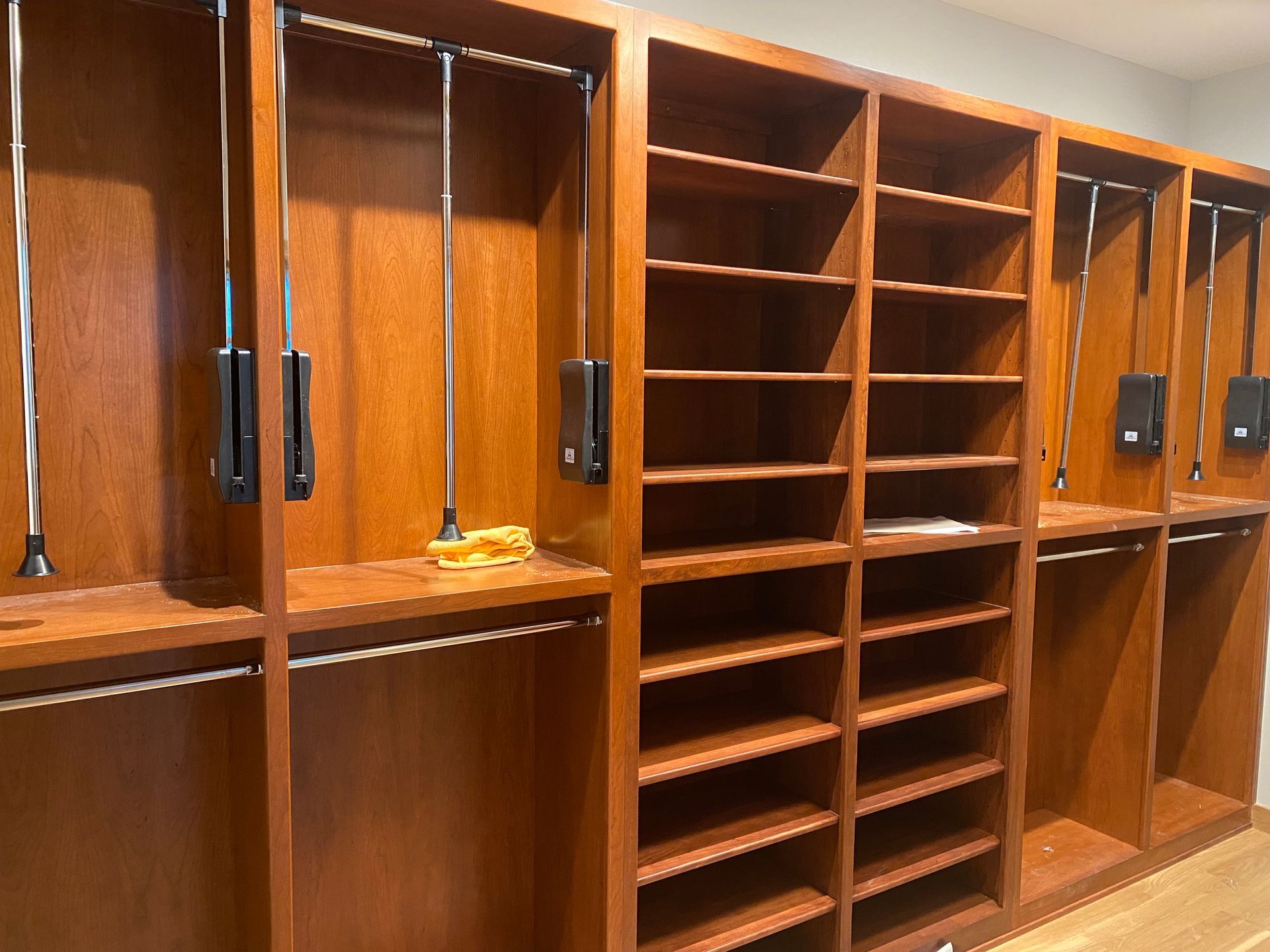 Wooden shelving wall with multiple cubbies and cabinets in a room, some sections empty and some with items.