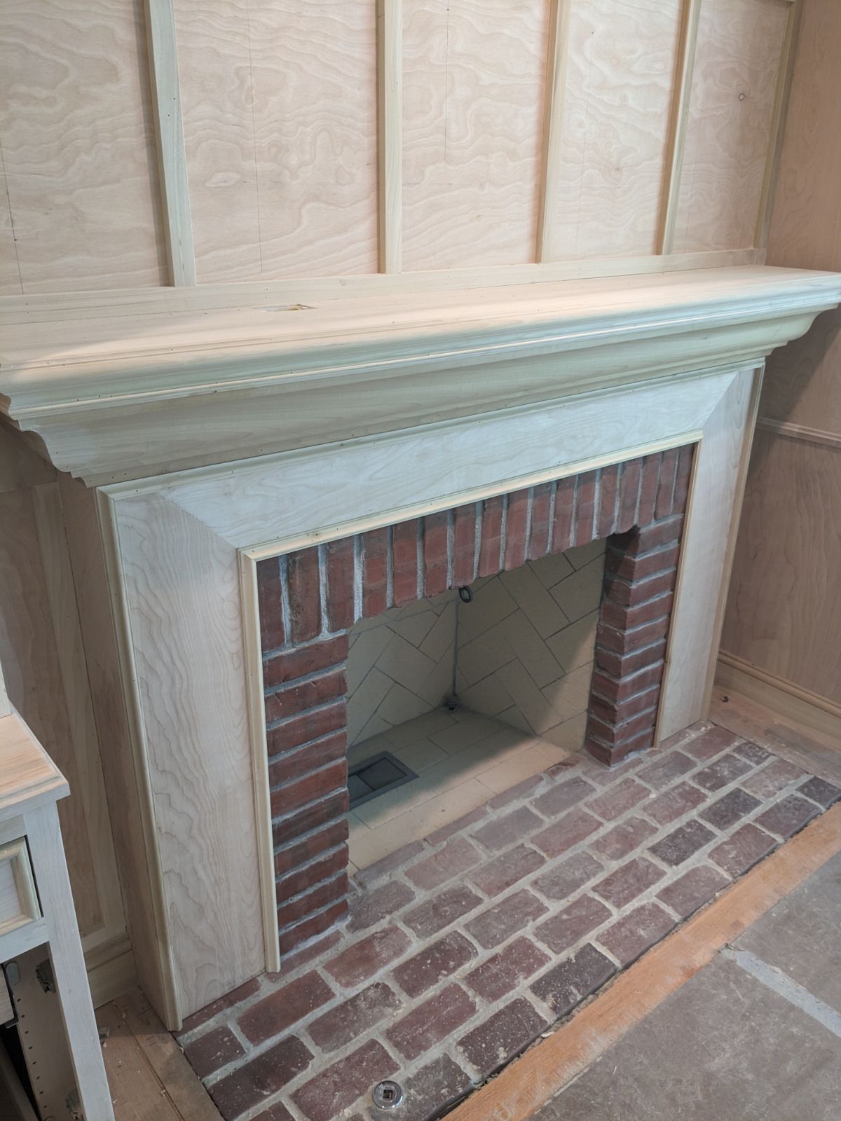 Brick fireplace with a white mantel and brick hearth in a wood-paneled room