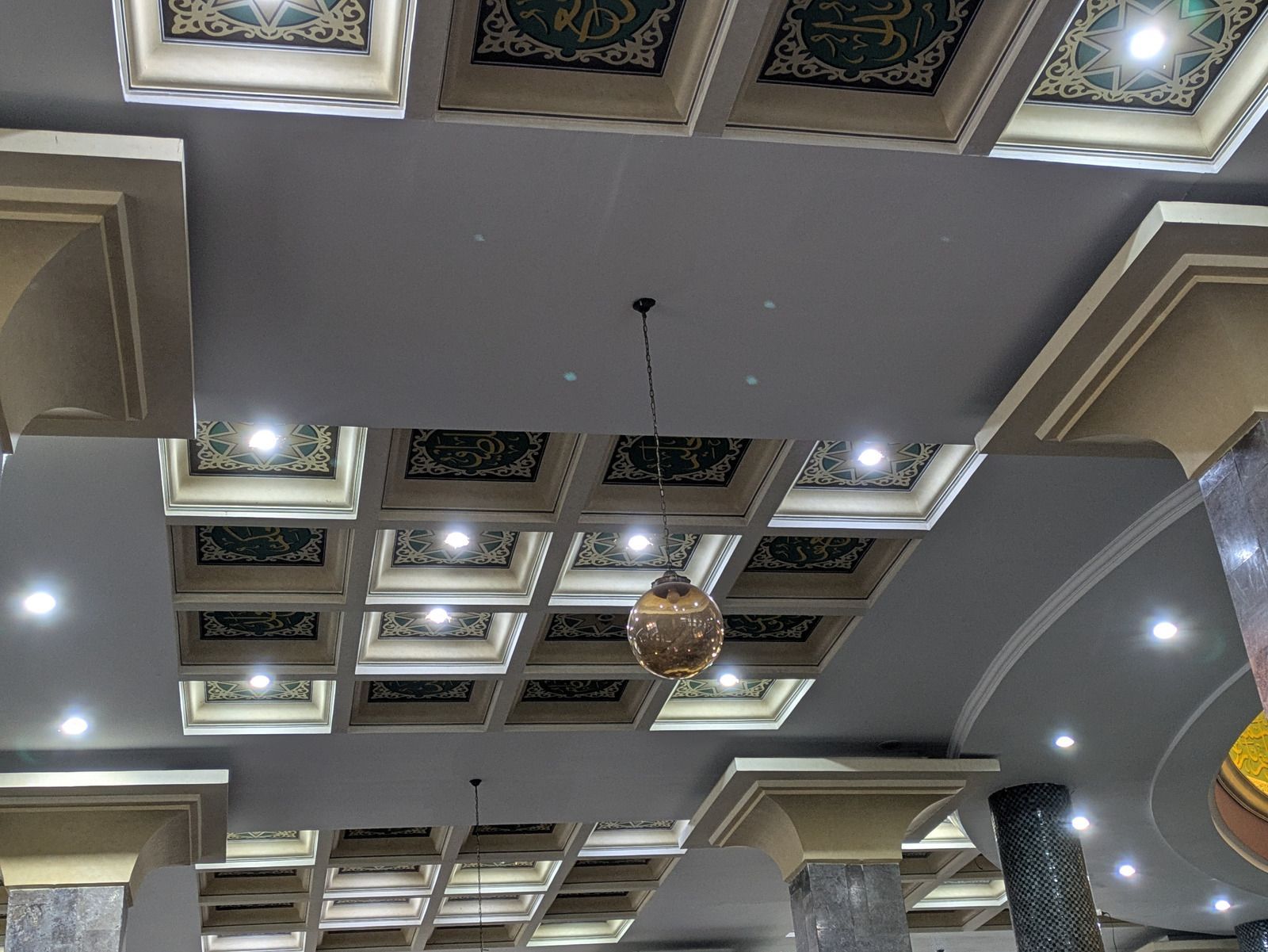 Decorative coffered ceiling with recessed lights and hanging pendant fixtures in a modern room