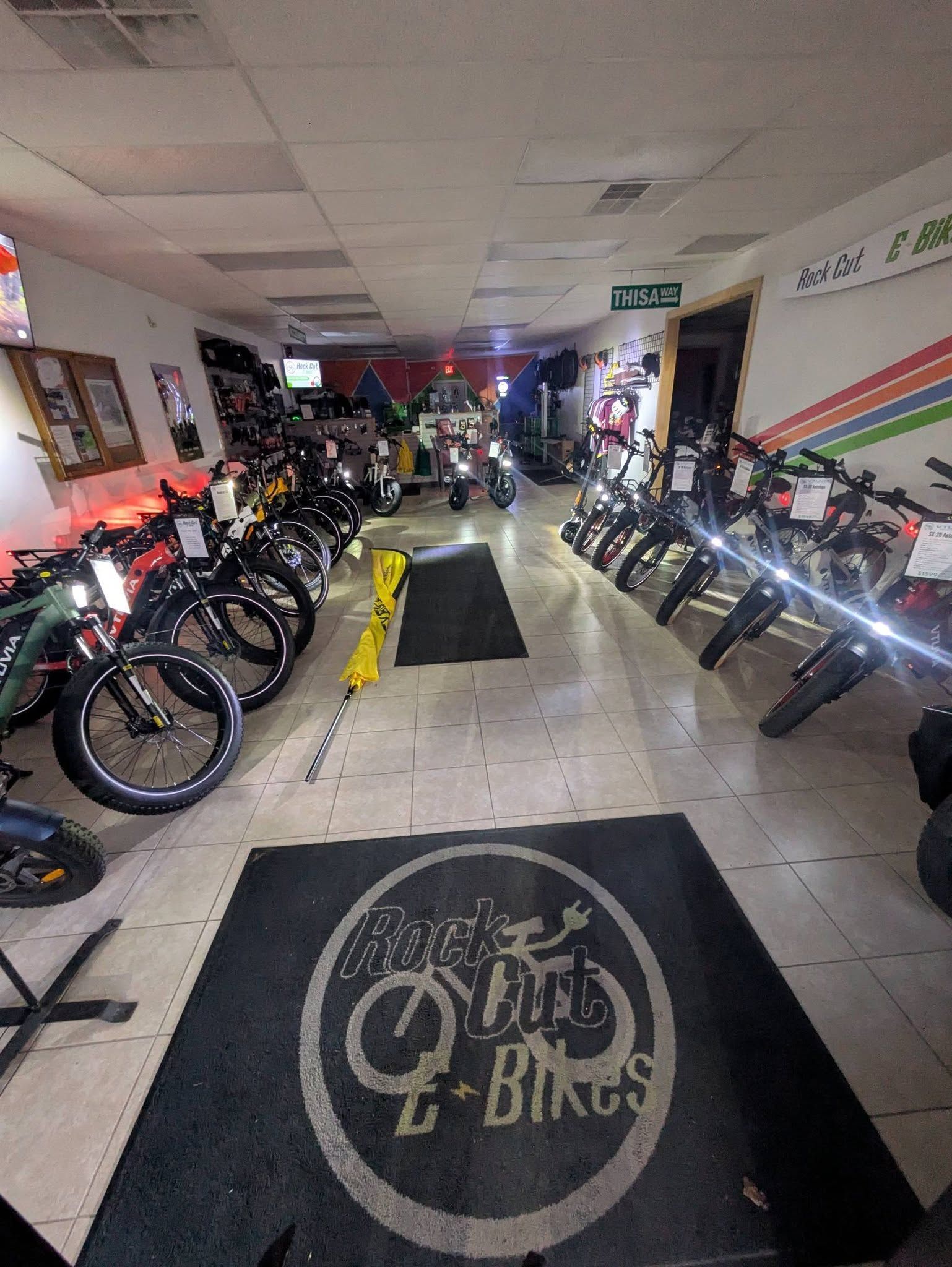 Bicycle shop interior with rows of bikes lined along both walls and a central aisle.