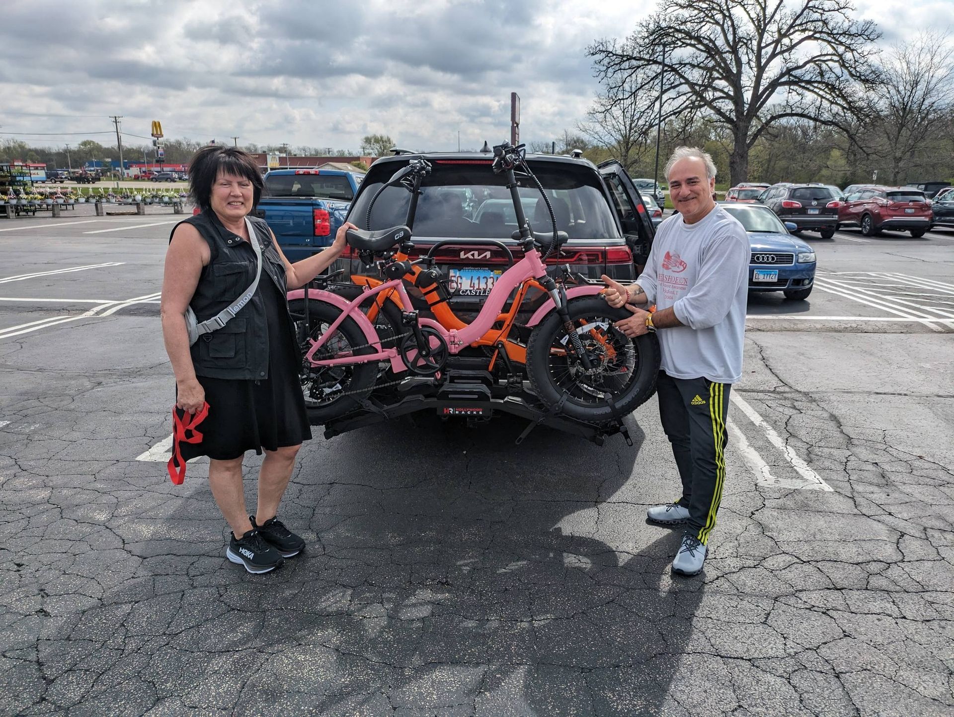 Two people standing beside a truck with an orange bike rack in a parking lot