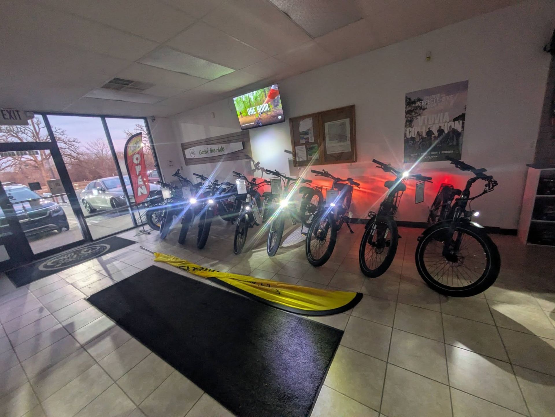 Row of dirt bikes displayed indoors under bright lights near a showroom entrance