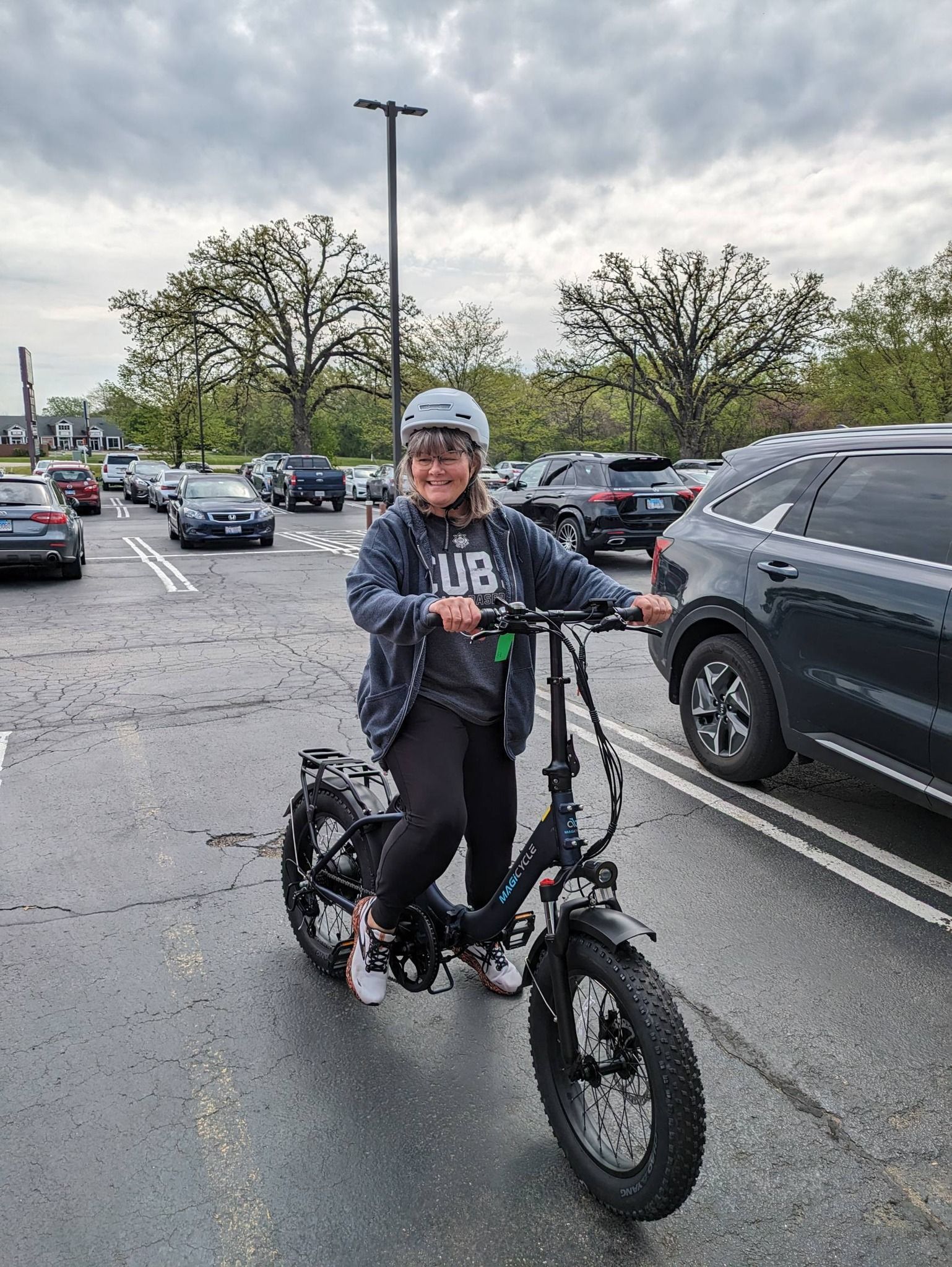 Person riding a fat-tire bike through a parking lot on a cloudy day.