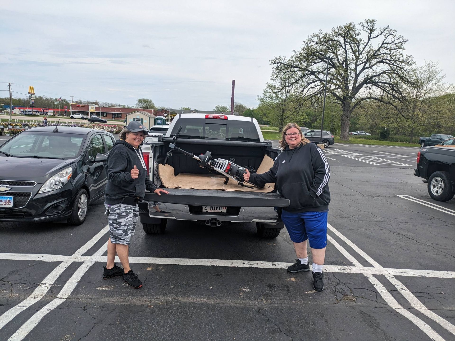 Two people loading a large object into a pickup truck in a parking lot