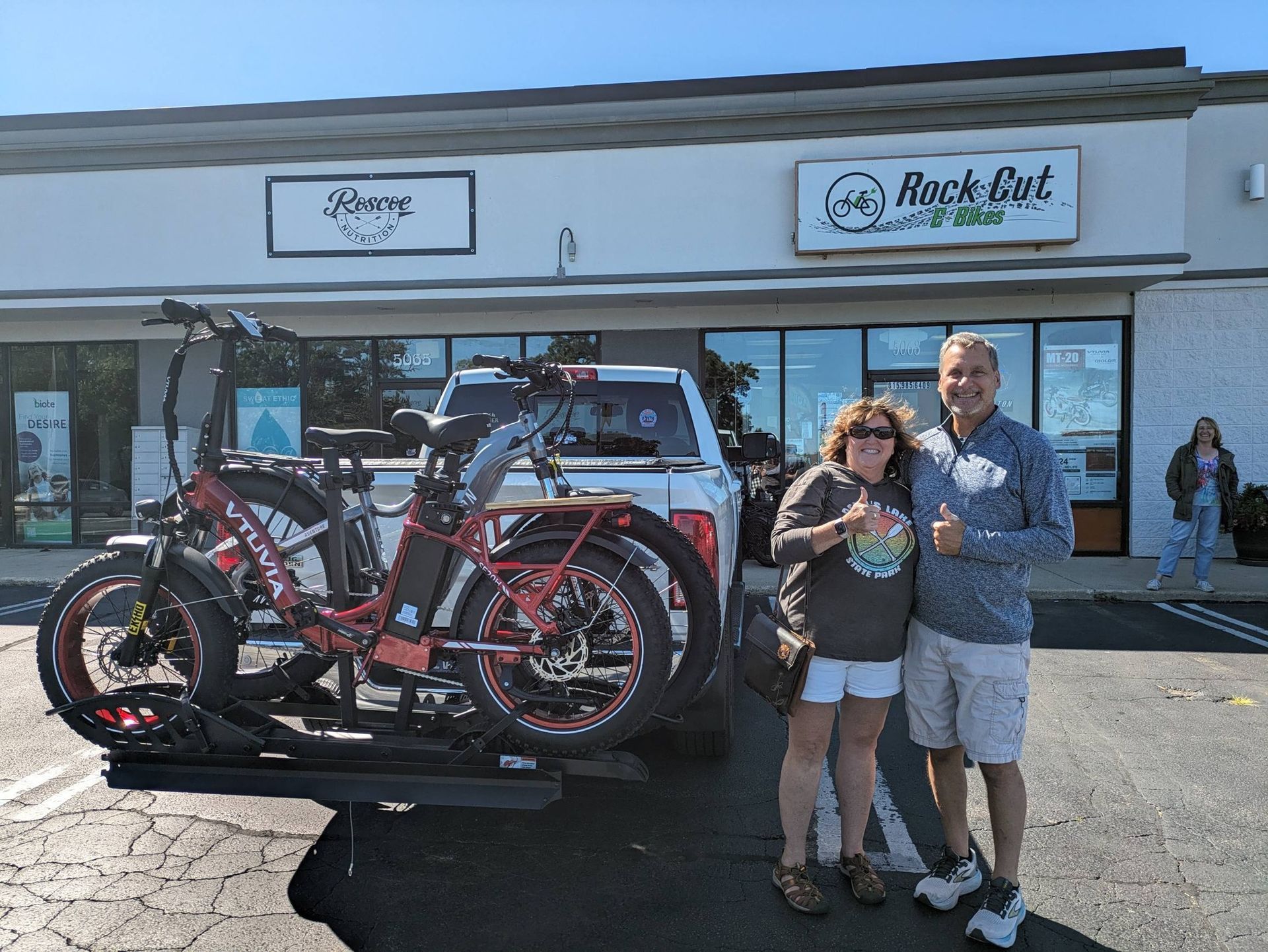 Two people standing by a truck loaded with a red bicycle outside a storefront