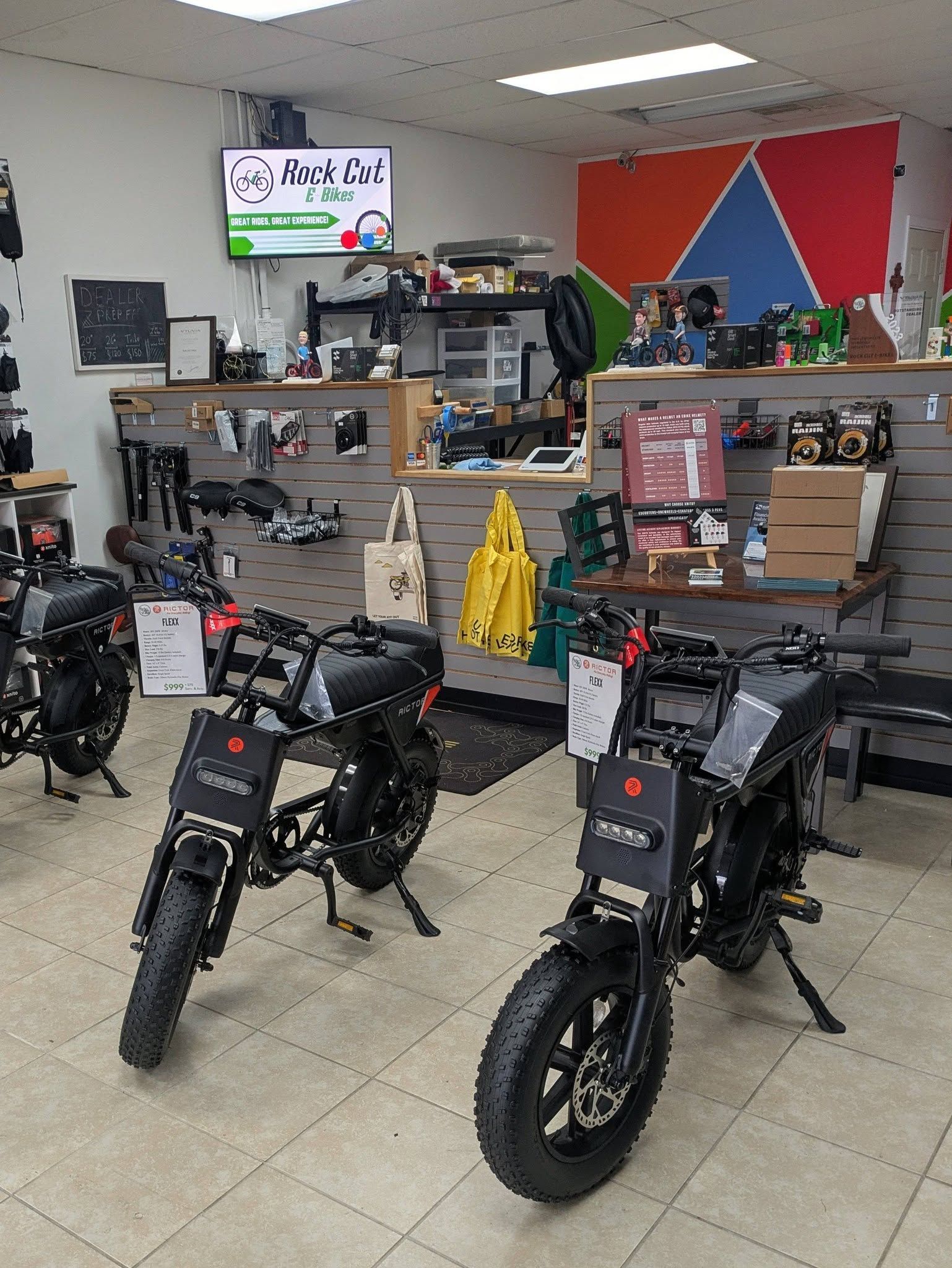 Indoor showroom with several black minibikes displayed on the floor and shelves in the background.