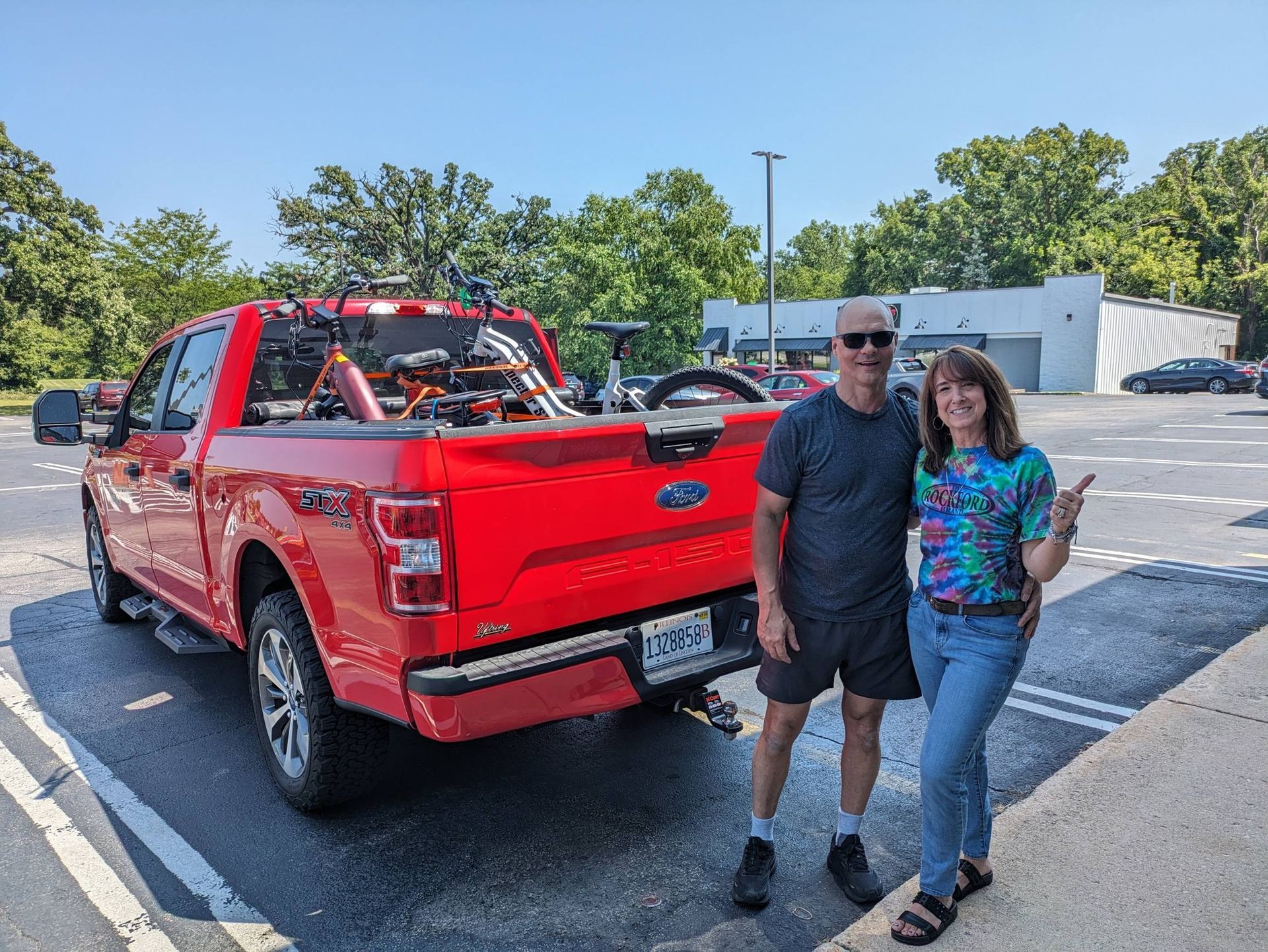Red pickup truck in a parking lot with two people standing beside it.