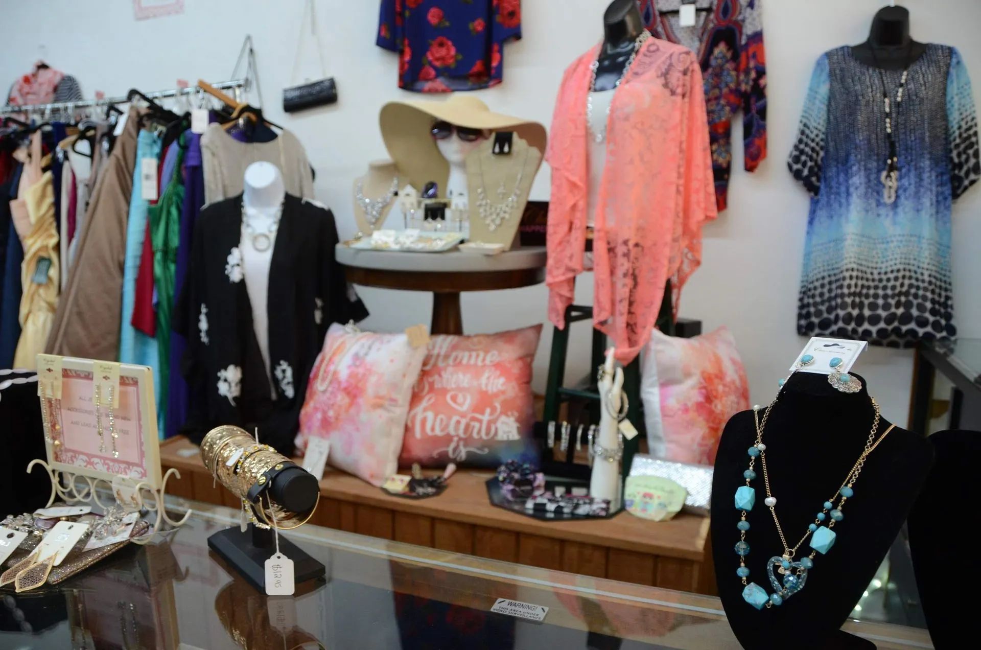 Clothing and jewelry display on mannequins and racks, featuring colorful tops, bags, and necklaces.