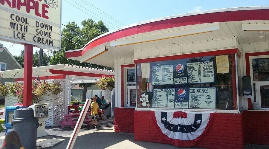 Drive-in ice cream stand with red-and-white trim and a “cool down with ice cream” sign