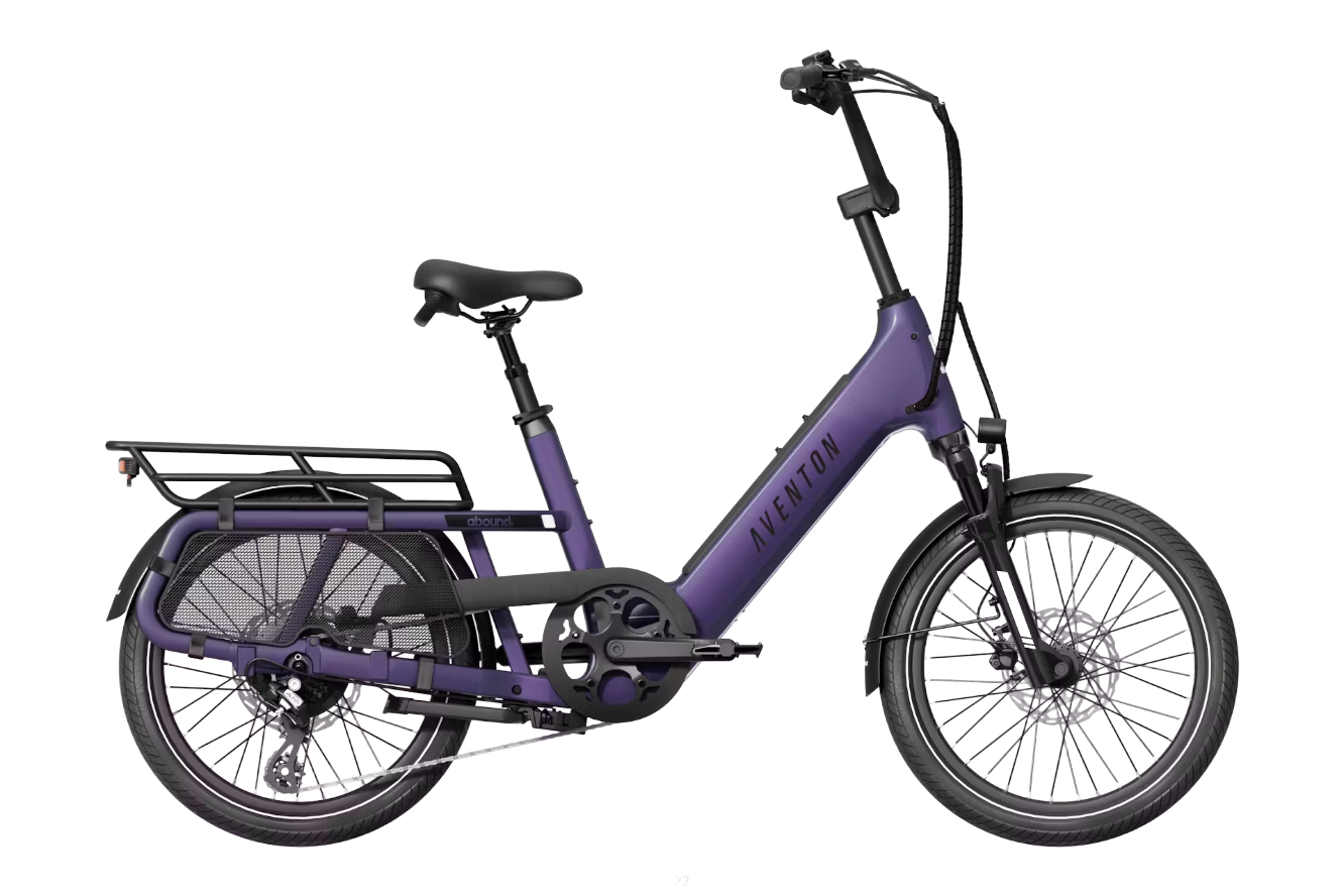Purple electric cargo bike with rear rack and black wheels on a white background