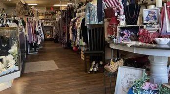 Narrow vintage shop aisle lined with clothing racks, decor, and wooden floor