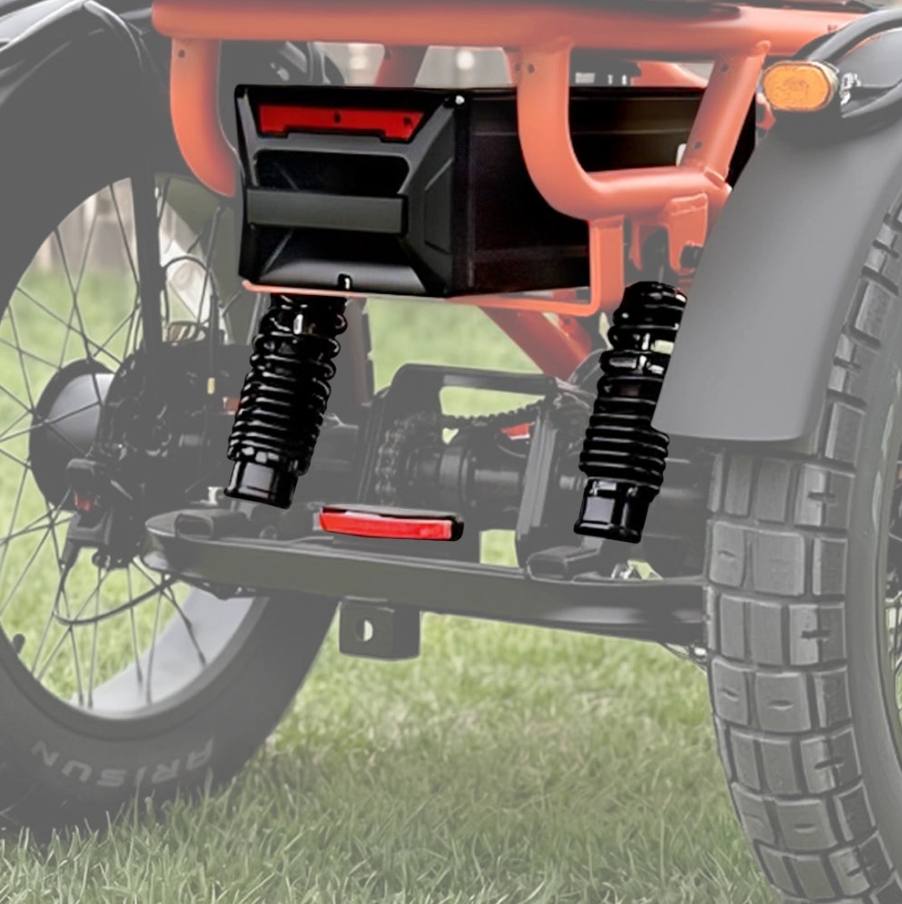 Front view of a vehicle with large front tires, black suspension springs, and an orange frame on grass