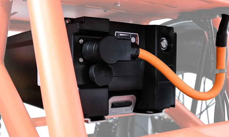 Black electrical module with orange cable mounted inside a machine frame