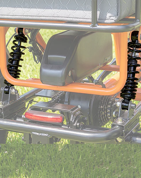 Close-up of a black and orange off-road vehicle suspension and seat over grass