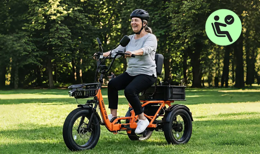 Person riding an orange three-wheeled bicycle on a grassy field, wearing a helmet.