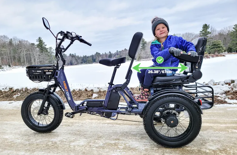 Child sitting on a blue adaptive tricycle in a snowy outdoor setting
