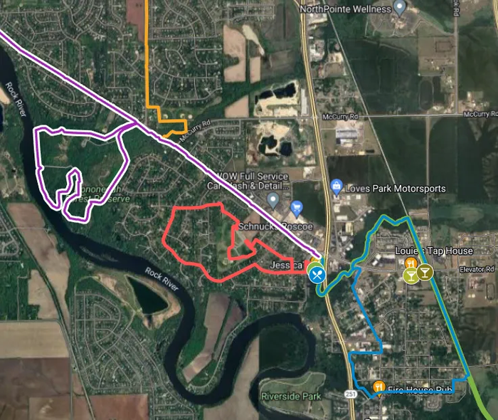 Satellite map with colored route outlines over roads, fields, and river near a town