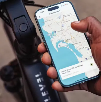 Hand holding a smartphone with a map app open near a car dashboard and charging cable