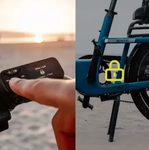 Finger pressing a bike lock remote near a blue bicycle on a beach at sunset