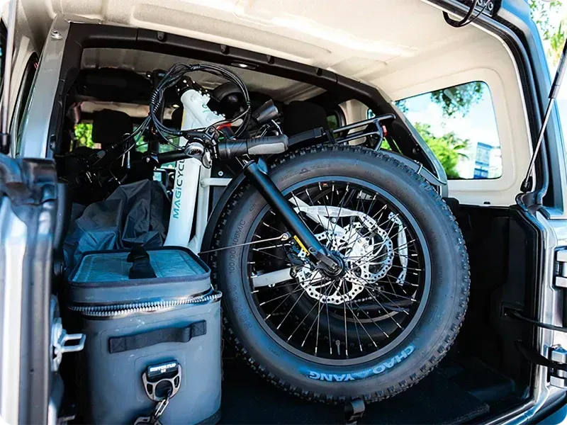 Cargo van packed with a fat-tire bicycle and camping gear, viewed from the rear opening