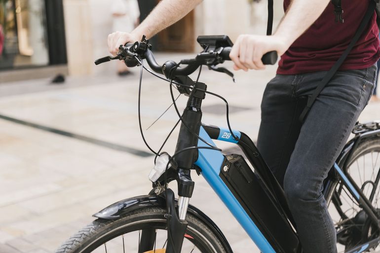Person riding a black and blue bicycle on a city street