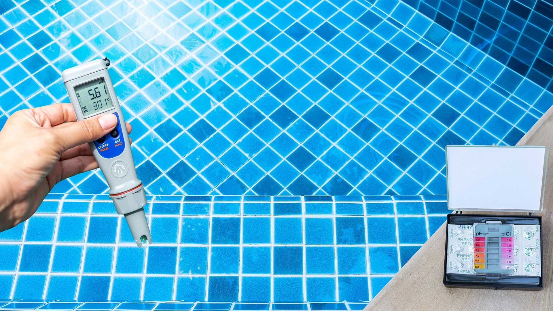 A person is holding a thermometer in front of a swimming pool.