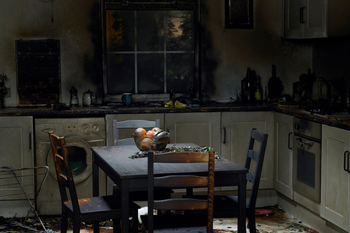 Fire Damage | Watervliet, MI | Mr. Cleans Restoration A kitchen interior heavily damaged by fire. Burnt walls, appliances, and a table with charred fruit.