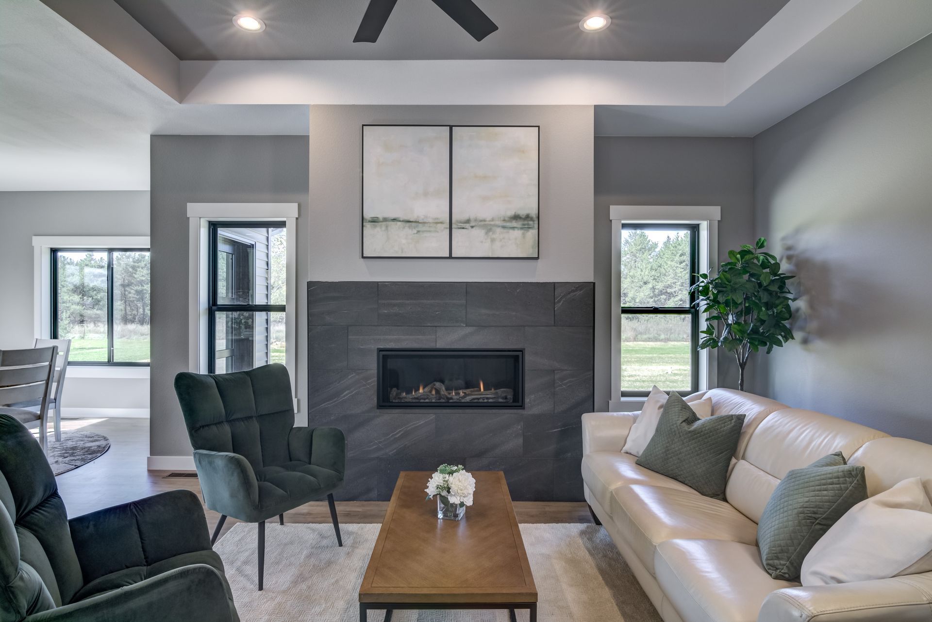 Modern living room with fireplace, gray walls, white sofa, and green accent pillows.