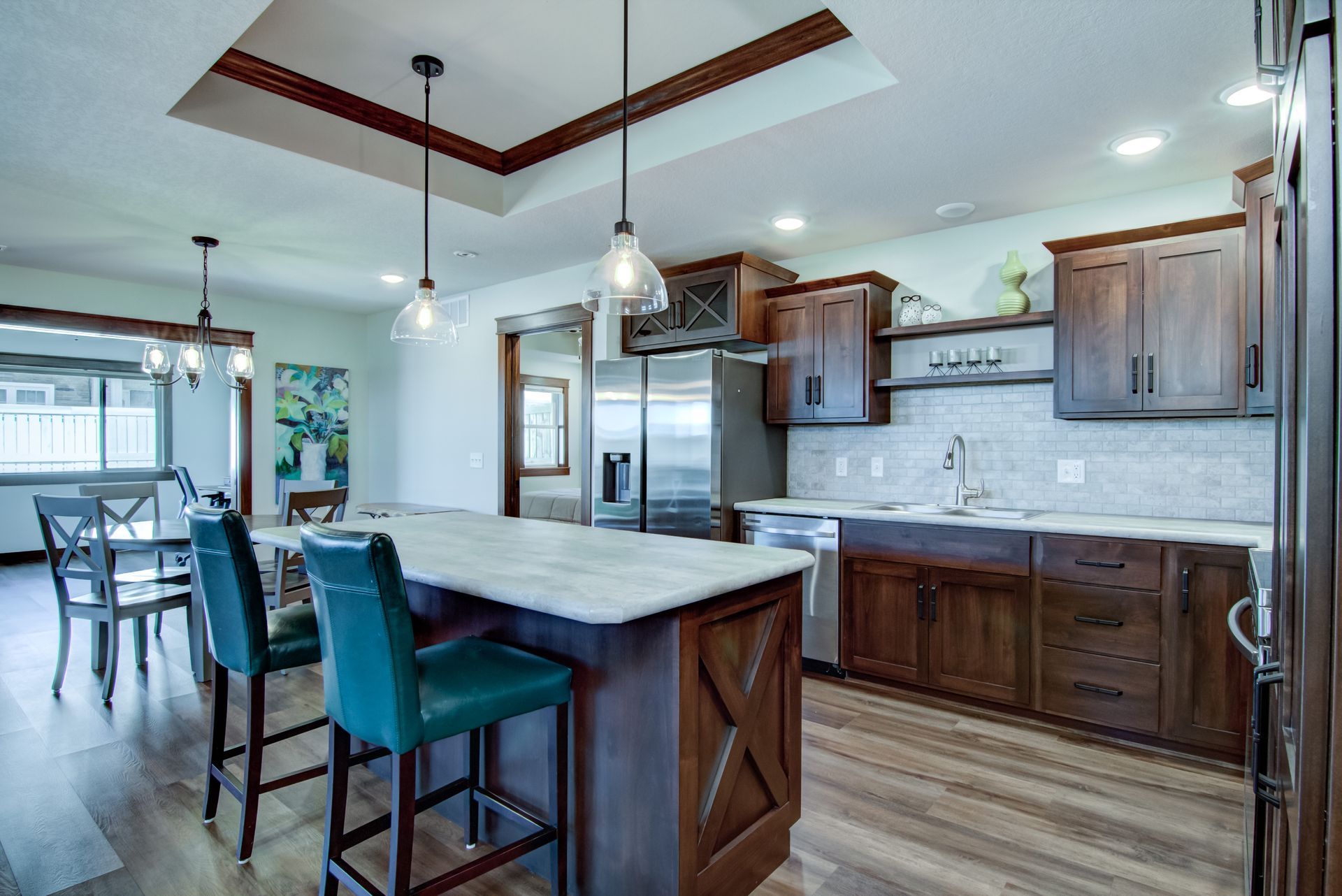 Spacious kitchen with wood cabinets, island with turquoise bar stools, and dining area with chairs.