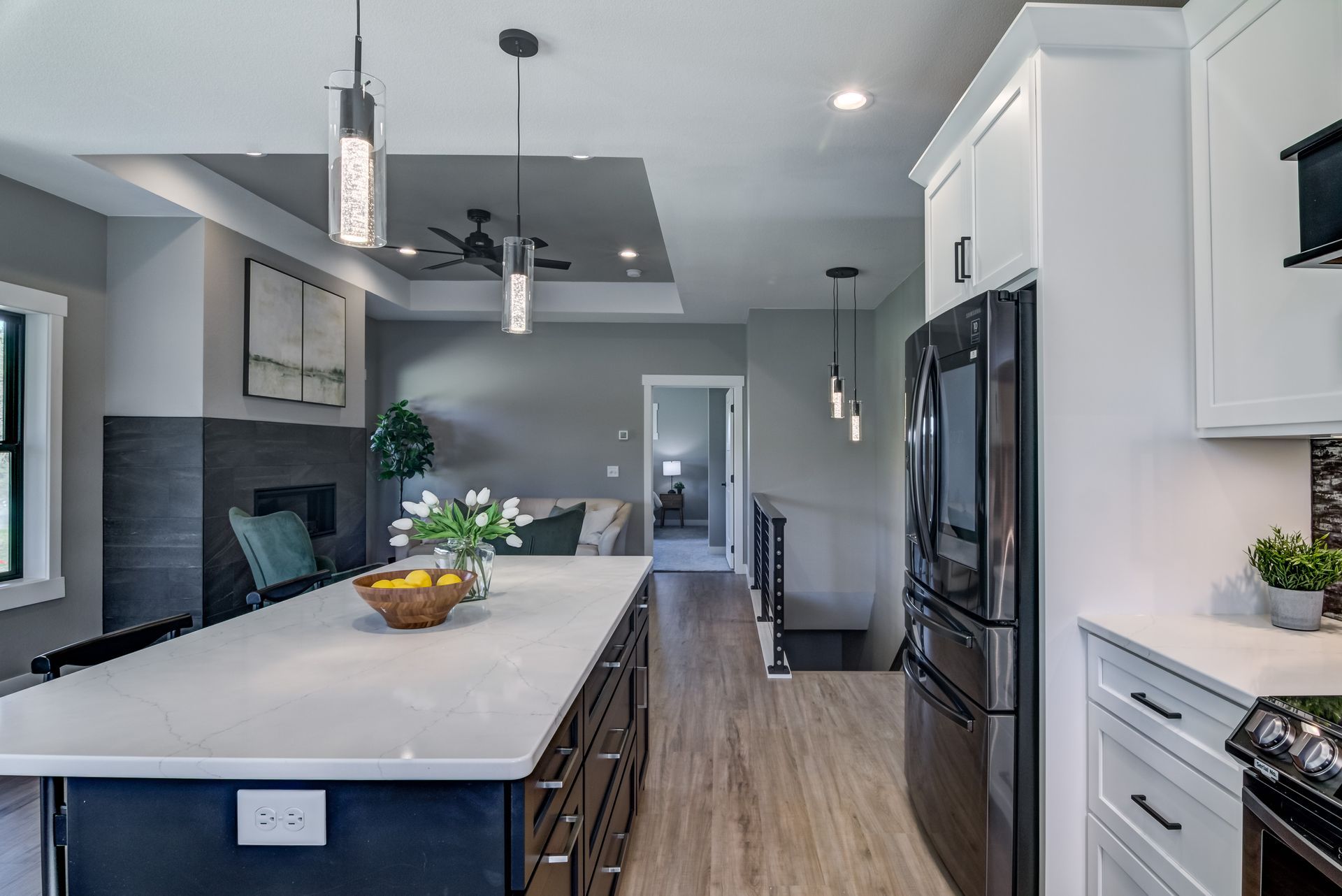 Modern kitchen with island, white countertops, black cabinets, and stainless steel appliances.