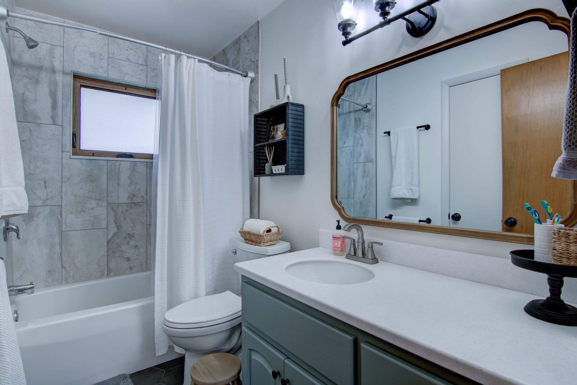 Bathroom with a white countertop, blue cabinet, and a framed mirror.