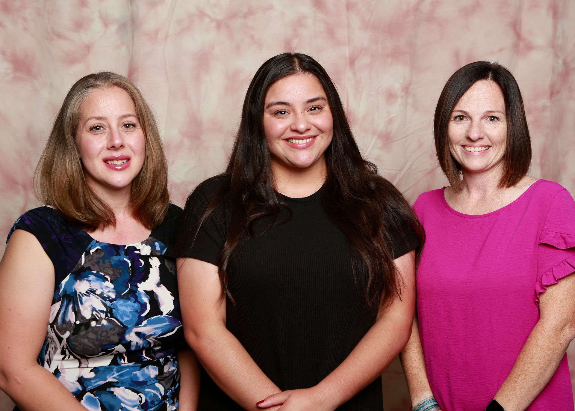 Three women are posing for a picture together and smiling for the camera.
