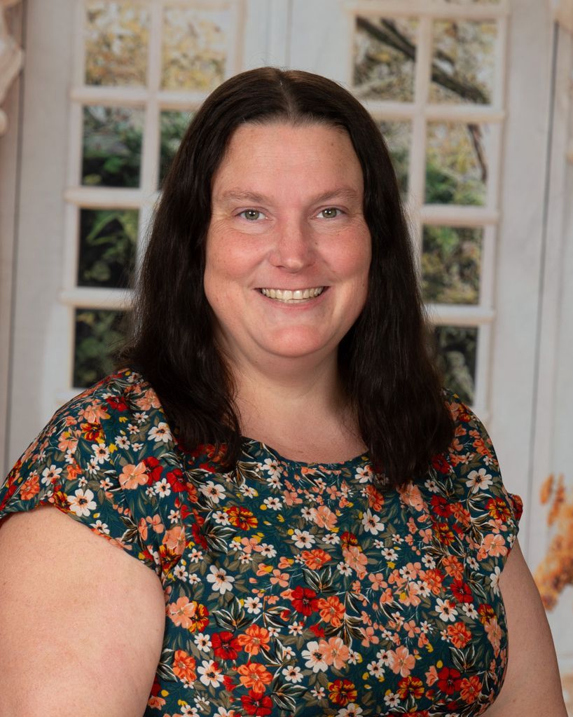 A woman with long hair is smiling and wearing a black and white shirt.