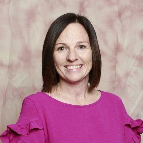 A woman in a purple shirt is smiling for the camera.