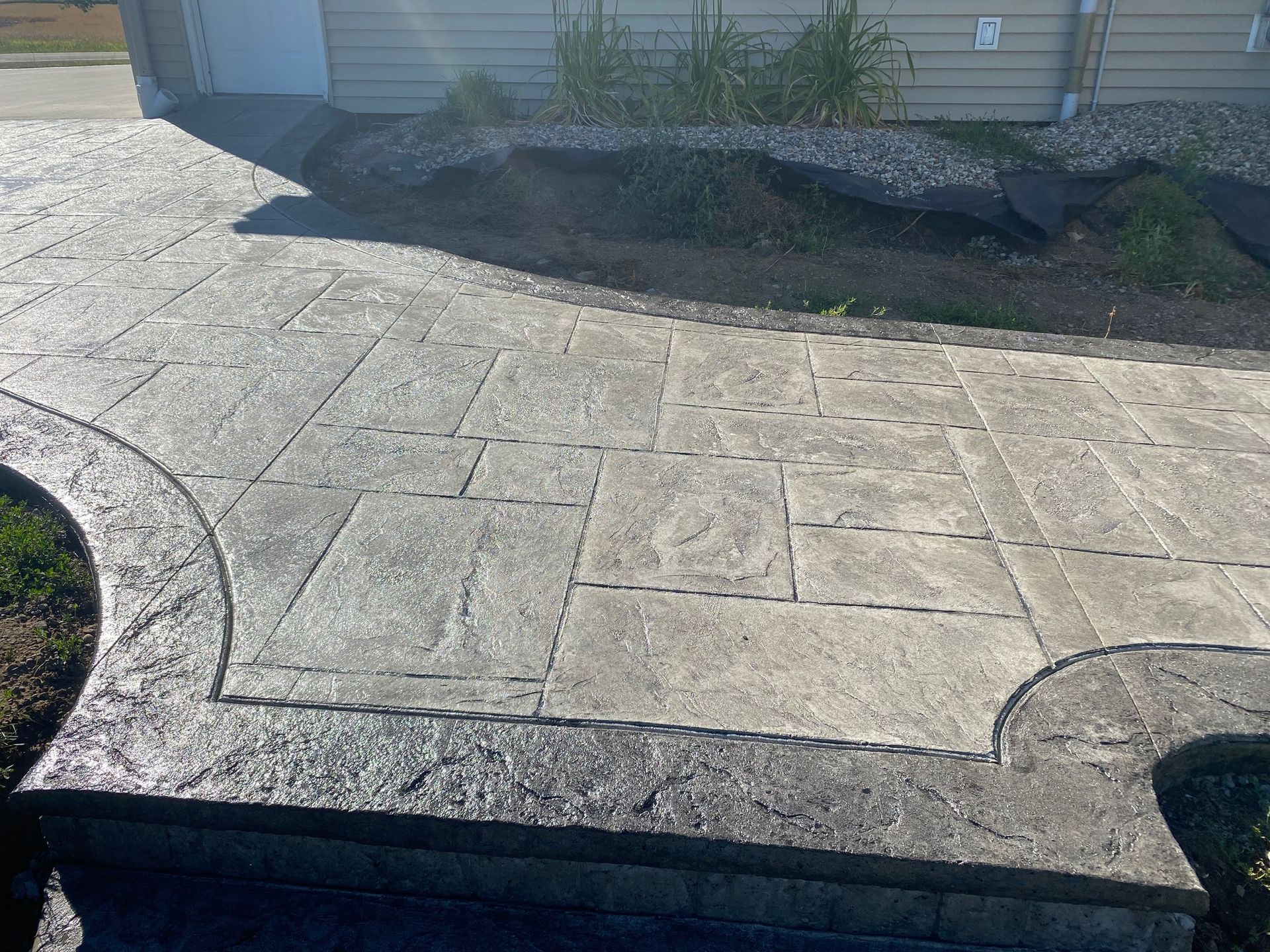 A concrete walkway leading to a house with a house in the background.