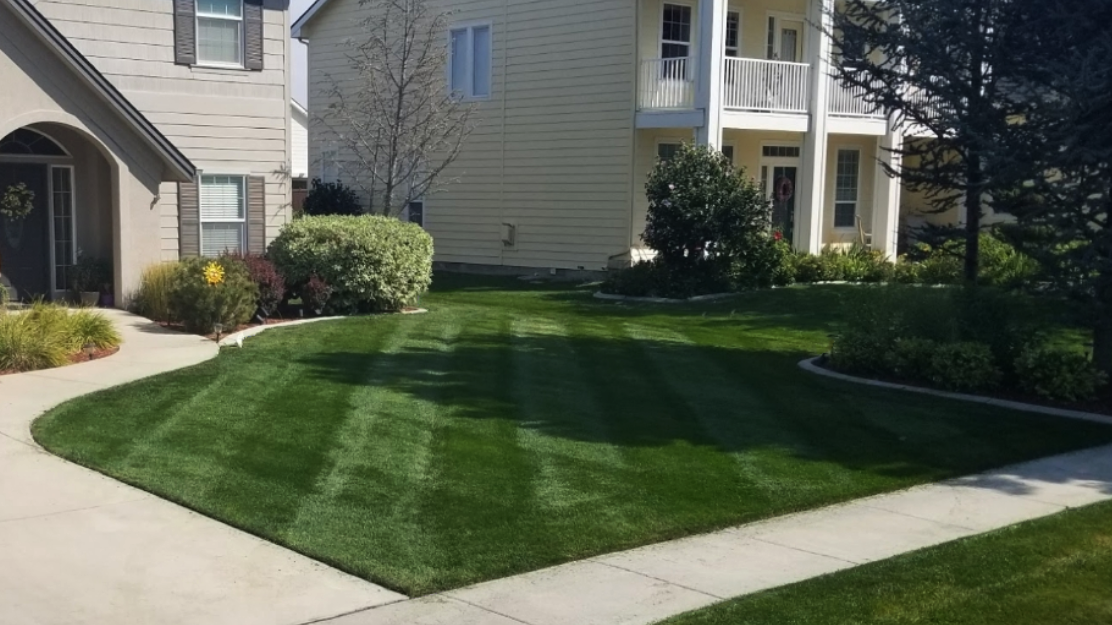 A house with a lush green lawn and a sidewalk in front of it.