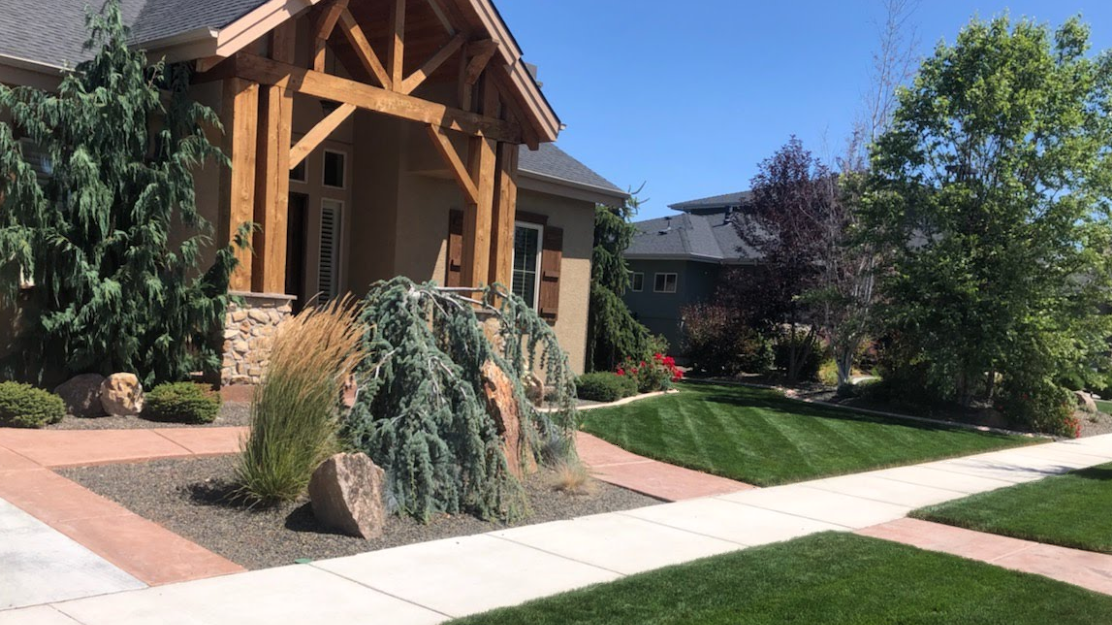 A large house with a wooden porch and a lush green lawn.