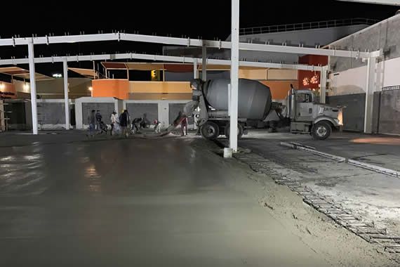 Un camión de cemento está vertiendo hormigón en un estacionamiento por la noche.