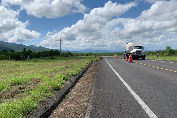 Un camión circula por una autopista al lado de un campo de hierba.